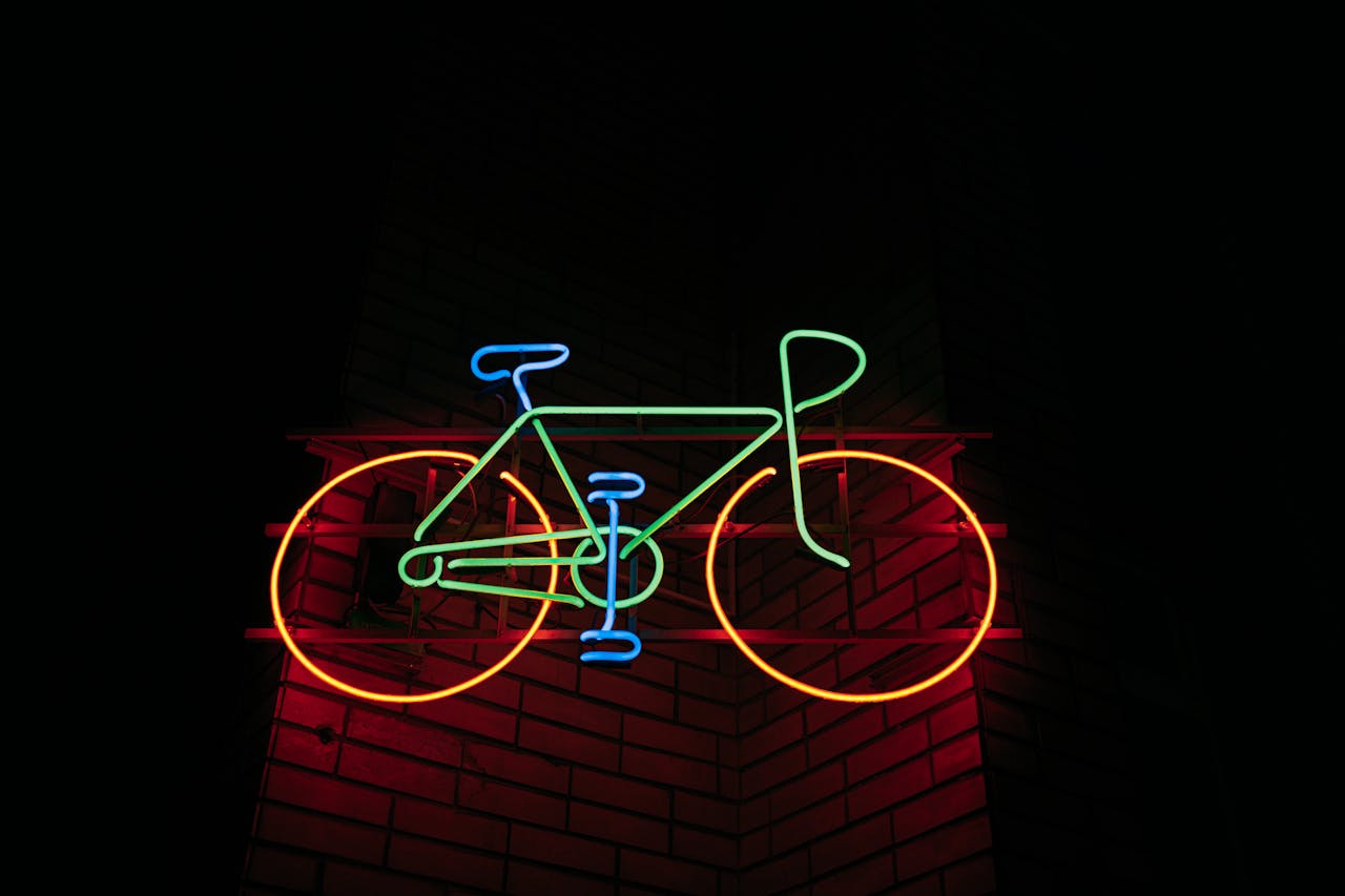 Vibrant neon bicycle sign glowing against a brick wall at night.